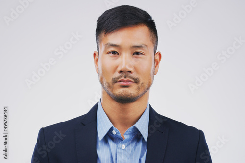 Hes a straight-faced businessman. Studio portrait of a handsome young businessman posing expressionless against a grey background.