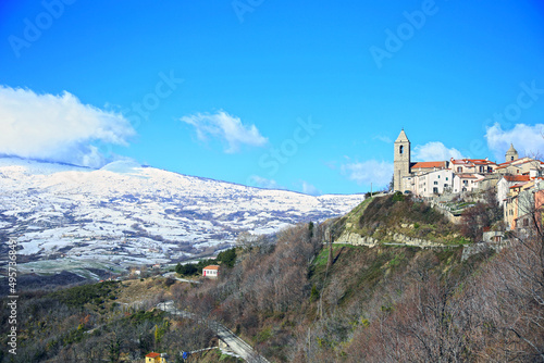 A glimpse of the village of Agnone, nestled among the snow-covered mountains, against the crystal clear blue sky, Agnone, Molise, Italy