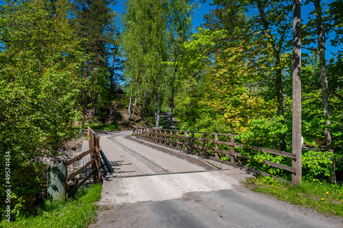 Wooden bridge across the river for pedestrians and cars. Landscape on a spring sunny day. Nõmeveski, Estonia. © Regina
