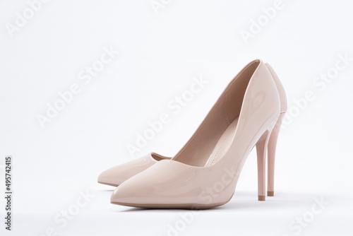 Elegant beige women's shoes with high heels. White background. Patent leather. Side view