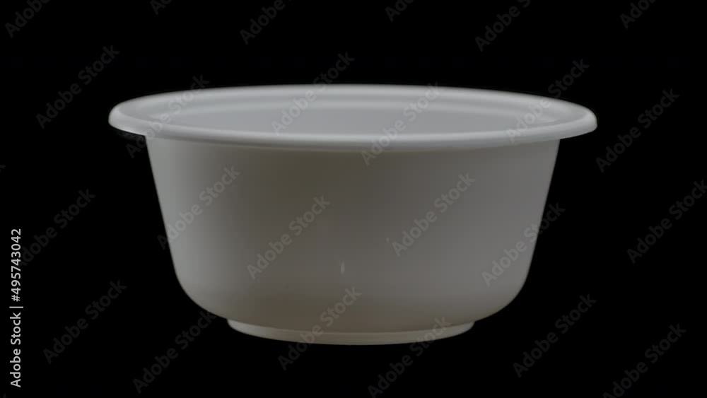 Disposable tableware, a bowl of ecological cornstarch on a black background Disposable tableware, a bowl of ecological cornstarch on a black background