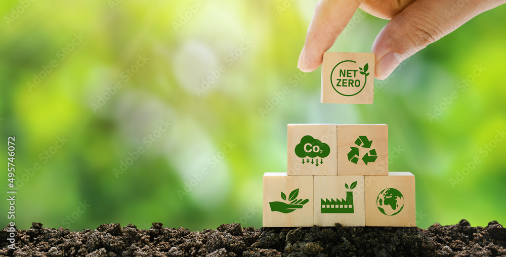 Net Zero and Carbon Neutral Concepts Net Zero Emissions Goals A climate-neutral long-term strategy Ready to put wooden blocks by hand with green net center icon and green icon on gray background. - obrazy, fototapety, plakaty 