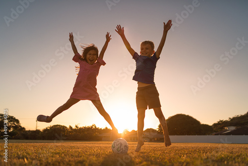 Multi racial boy girl children portrait smiling happy jumping for joy in an outdoor sunset setting. 