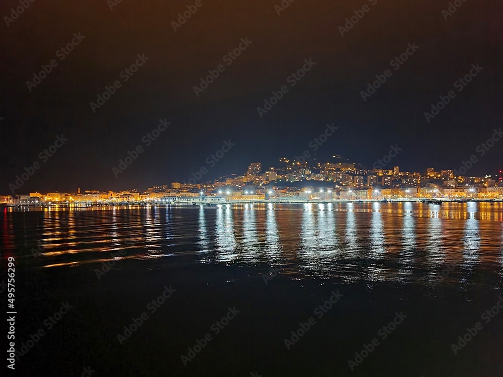 Night panorama of the port city from the side of the sea raid