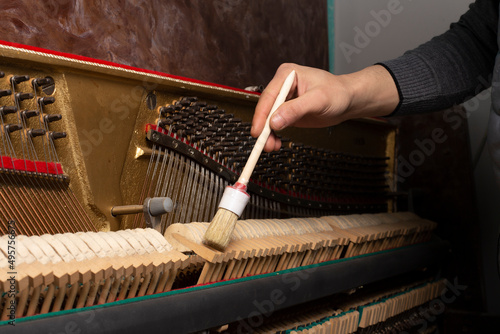 closeup of hand and tools of tuner working on grand piano.
