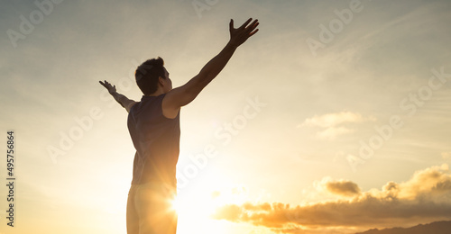 Happy young strong man feeling at peace with arms up to the sky. Nature getaway, peace in nature 