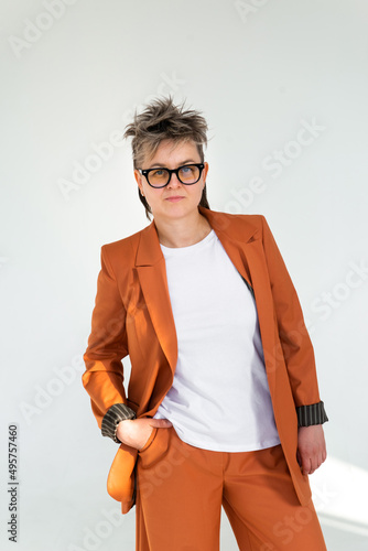 young emotional non binary person wearing orange color suit posing at studio photo