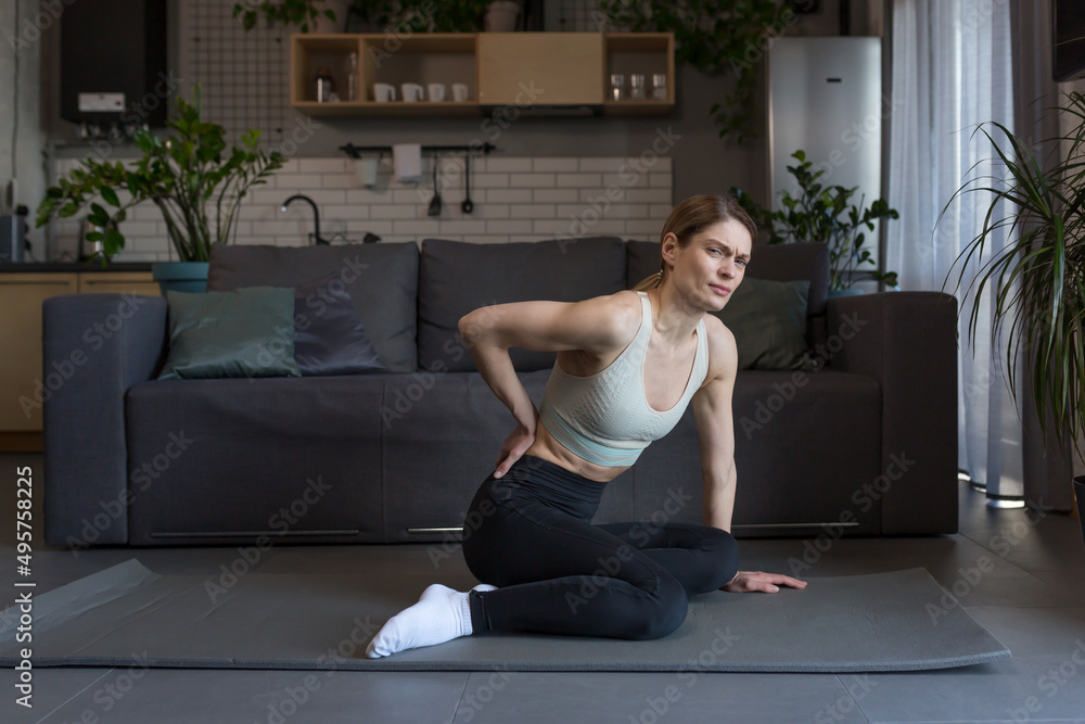 Obraz premium A female athlete injured her back during morning exercises at home