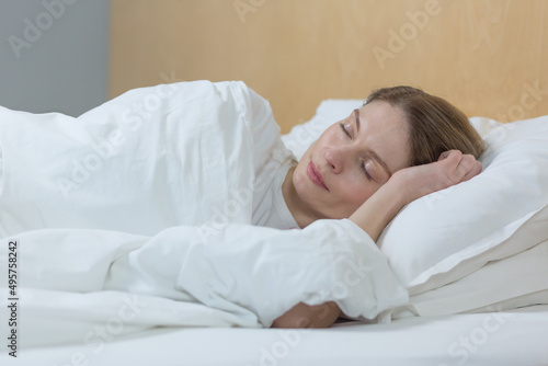 Woman sleeping at home under a blanket with eyes closed resting