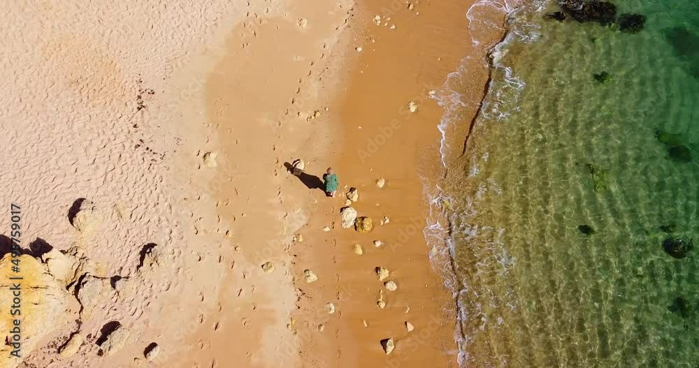 Camera following a woman who is walking alone on the beach, camera