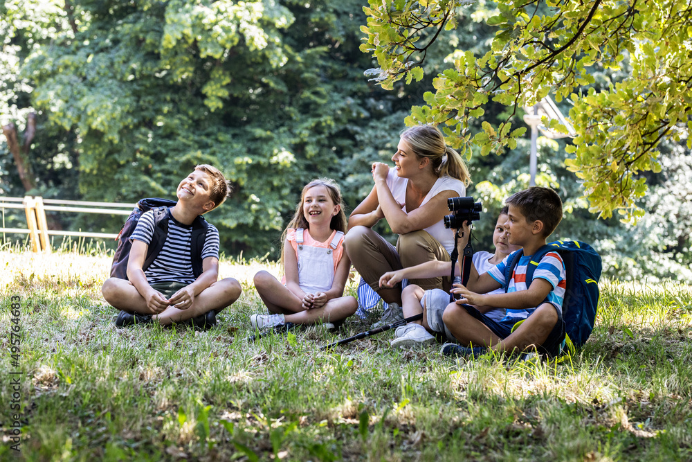Group of children sitting on grass in the forest with their teacher.They learn about nature and wildlife.
Group of children sitting on grass in the forest with their teacher.They learn about nature and wildlife.