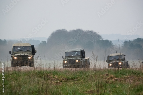 Fototapeta a small convoy British Army Land Rover Defender Wolf medium utility vehicles in