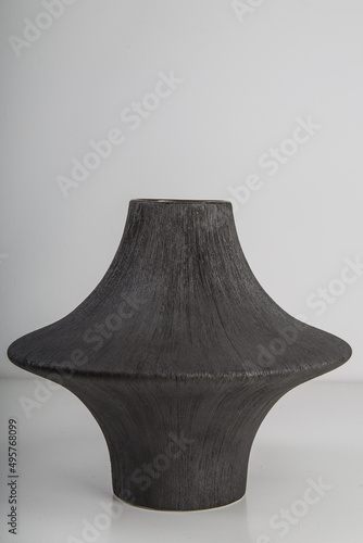 Selective focus shot of a dark-colored and weird-shaped ceramic vase on a grey surface photo