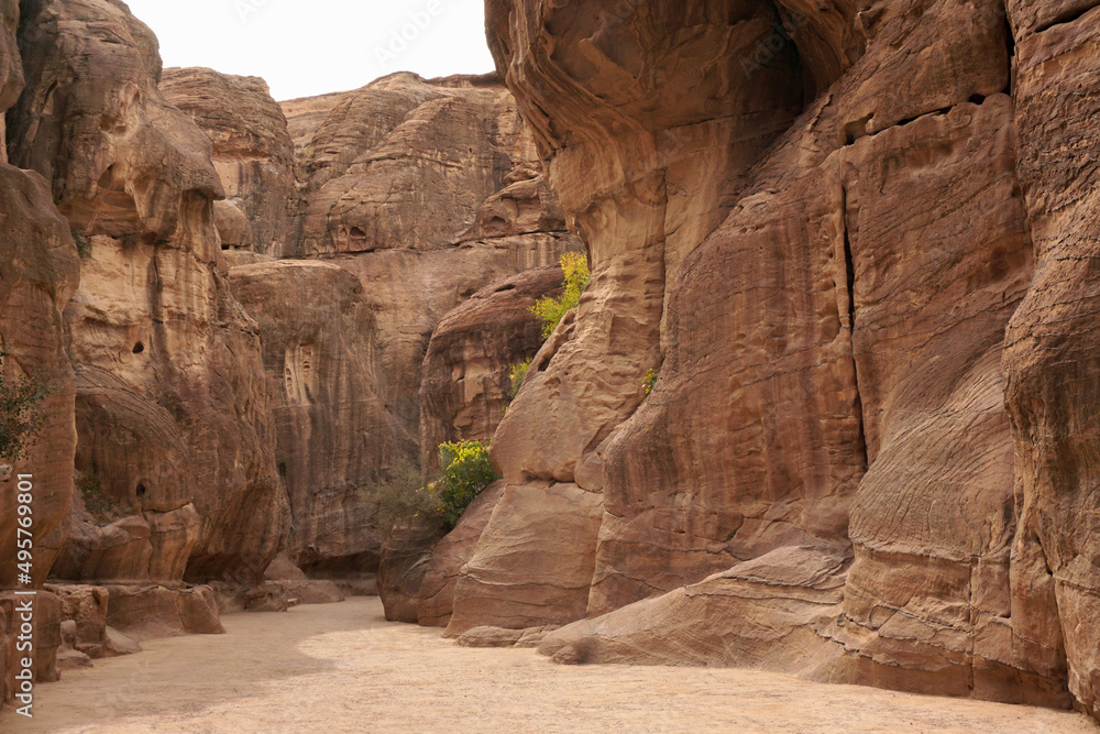 A narrow gorge between red relief mountains on the way to ancient Petra, Jordan