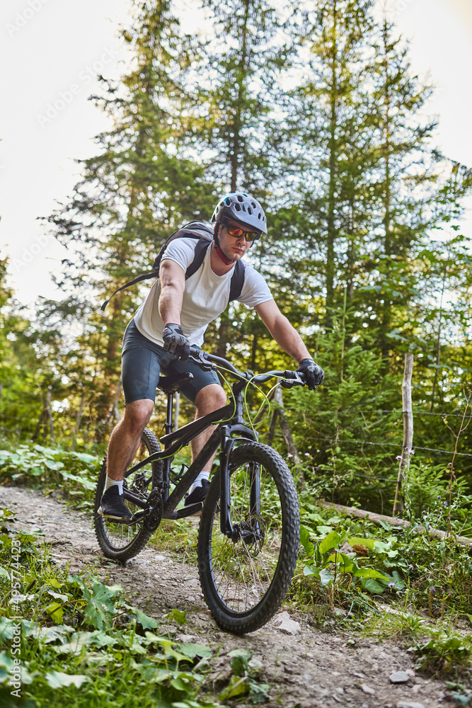 Cyclist Riding the Bike on the Trail in the Forest. Man cycling on enduro trail track. Sport fitness motivation and inspiration. Extreme Sport Concept. Selective focus