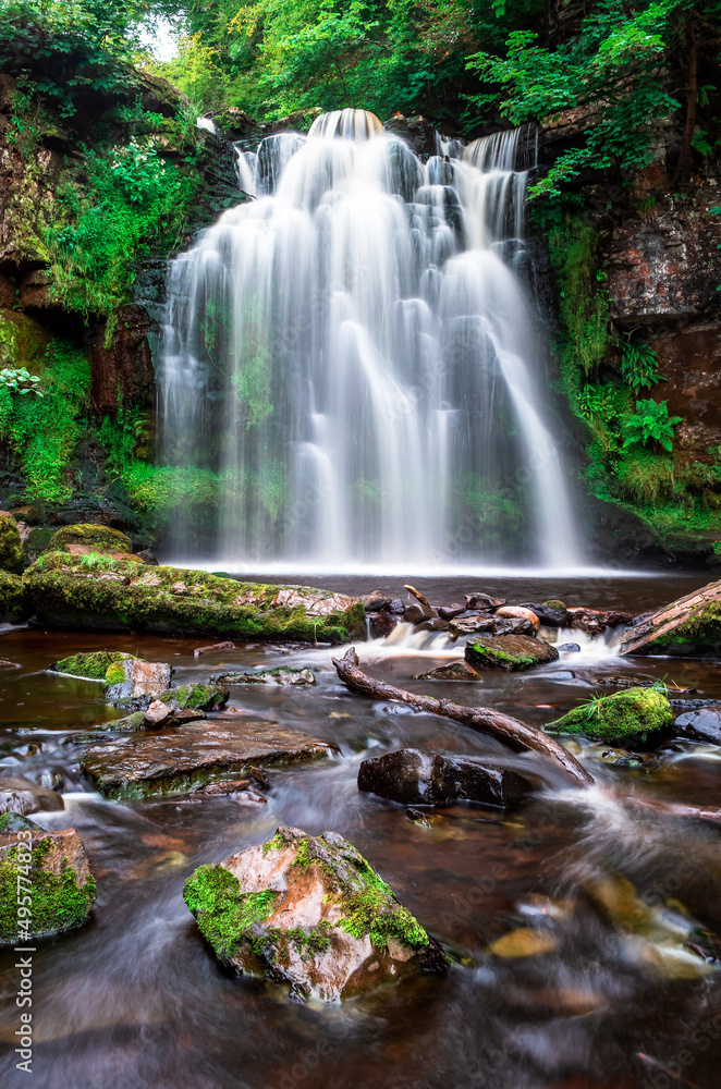 Fototapeta premium A waterfall flows, Lynn Falls, Caaf Water, Lynn Glen, Dalry, North Ayrshire, Scotland, UK