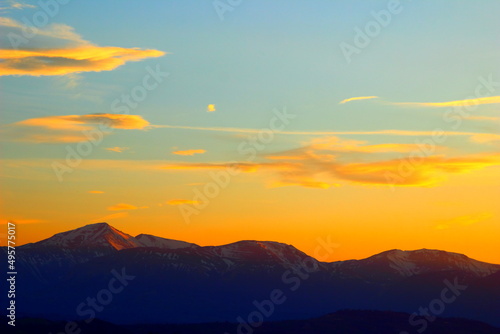 The incredible Apennines with snow-capped peaks under the yellow-blue sky with some clouds during sunset in Monte Vidon Corrado