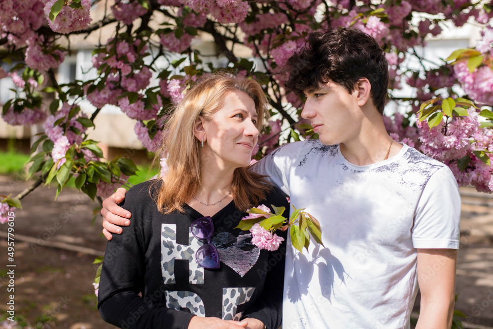 The woman looks with joy and pride at her teenage son, the mother is glad that she has such a beautiful, intelligent son. The concept of communication, parents and adolescent children