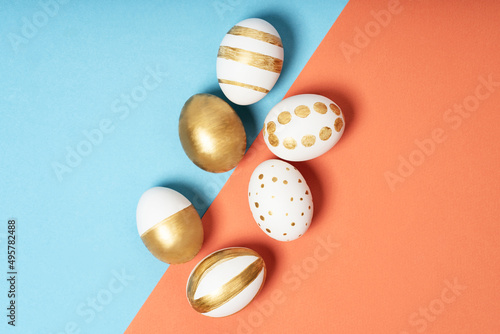 Hand-drawn easter eggs on blue and orange pastel background. Many easter eggs flat lay background.