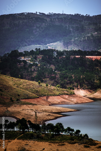 Vertical shot of the Umiam lake surrounded by many trees in the background of mountains. photo