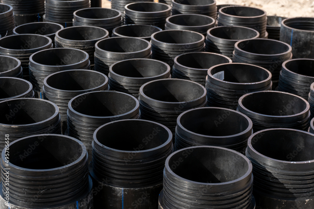 New plastic black pipes for drinking water are stored outside. Repair of water supply in the city and replacement of old pipes with new modern ones made of polyethylene. New plastic black pipes for drinking water are stored outside. Repair of water supply in the city and replacement of old pipes with new modern ones made of polyethylene.