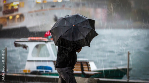 Photos Male holding umbrella by the sea on a rainy day