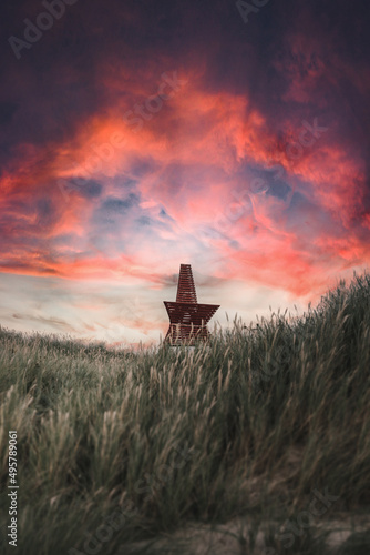 Vertical shot of a field udner the pink and purple clouds in the sky photo