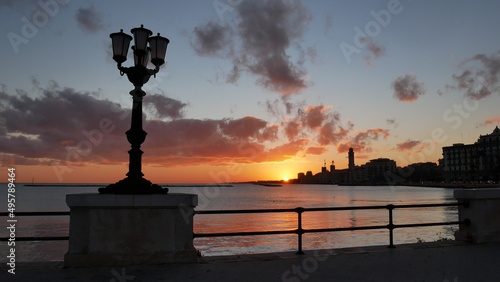 Bari, Lungomare, sorgere del sole nella bellissima città, lampione spento, silhouette profilo scuro nero, Sud, colore rosa, rosso, Puglia, Italia,	 photo