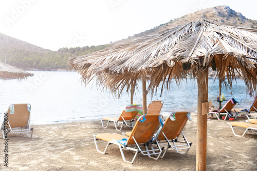 Fototapeta Naklejka Na Ścianę i Meble -  Empty beach in Greece. Sun loungers and straw umbrellas