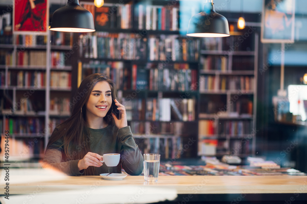 Woman using smartphone and drinking coffee in a cafe. Woman using smartphone and drinking coffee in a cafe.