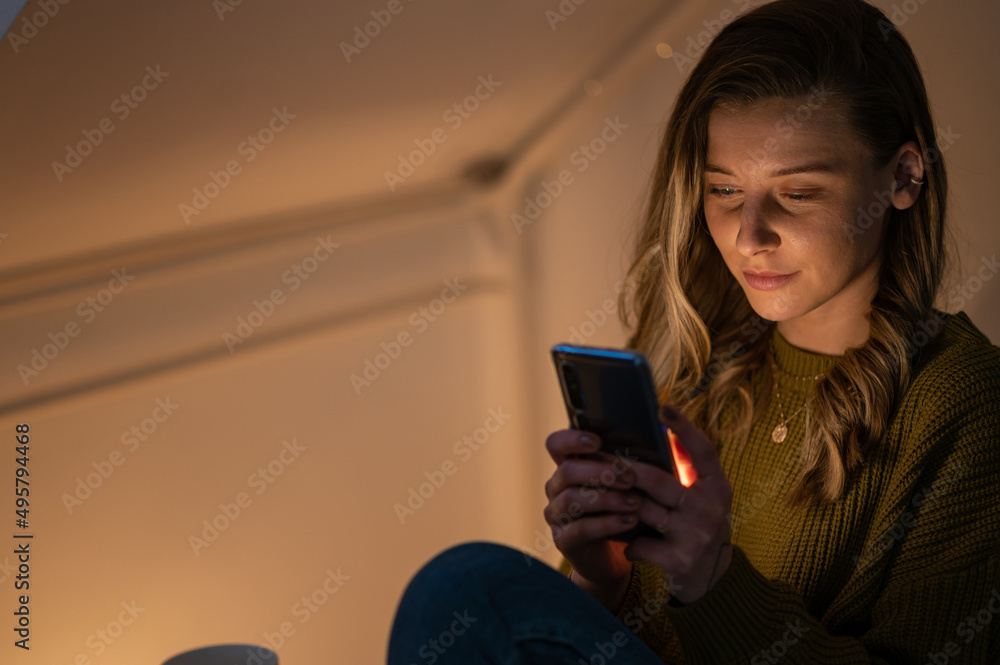 Woman using smartphone while sitting on the sofa at home