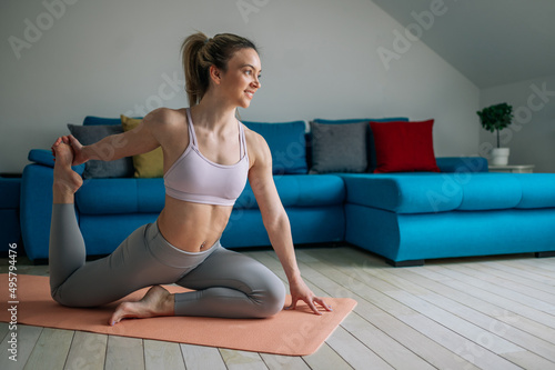 Woman practicing yoga at home while doing the pigeon pose