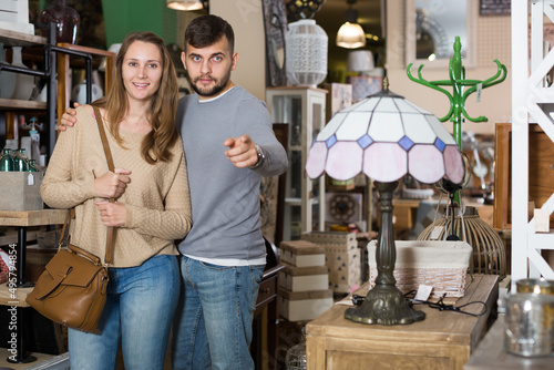 Loving couple looking for stylish knickknacks in shop of secondhand furniture