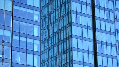 Glass building with transparent facade of the building and blue sky. Structural glass wall reflecting blue sky. Abstract modern architecture fragment. Contemporary architectural background.