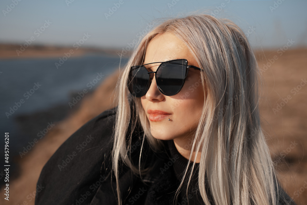 Outdoor portrait of beautiful girl with blonde hair, wearing sunglasses.