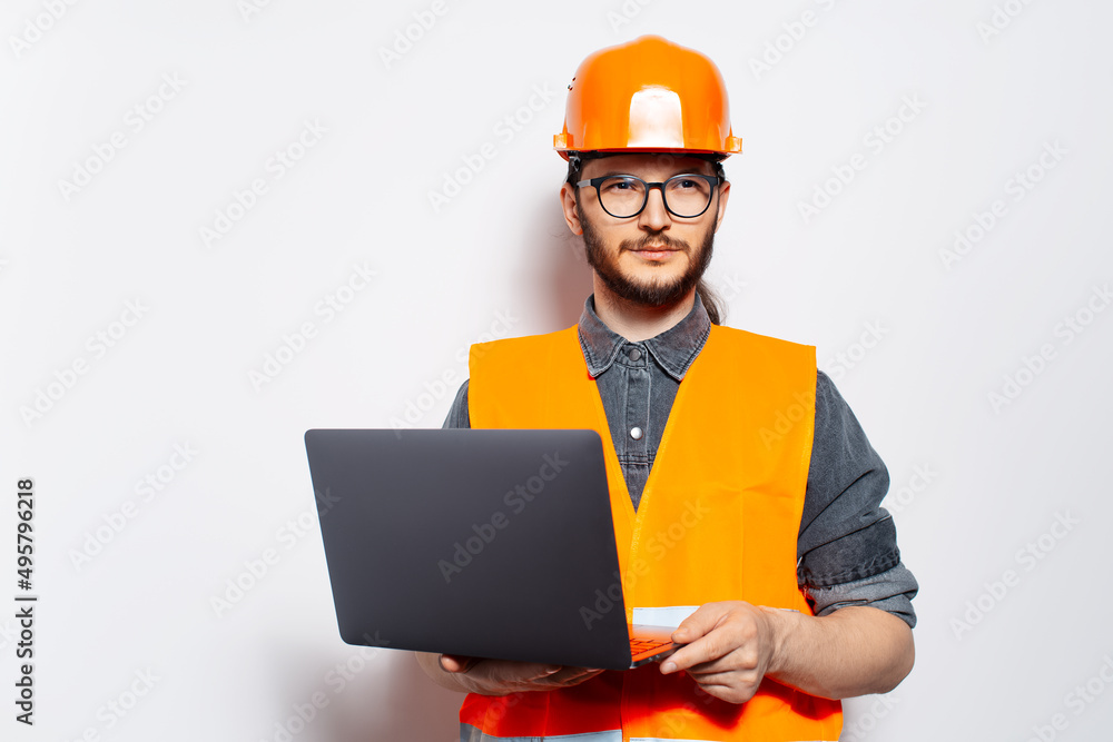 Studio portrait of young confident construction worker on white, using laptop. Studio portrait of young confident construction worker on white, using laptop.