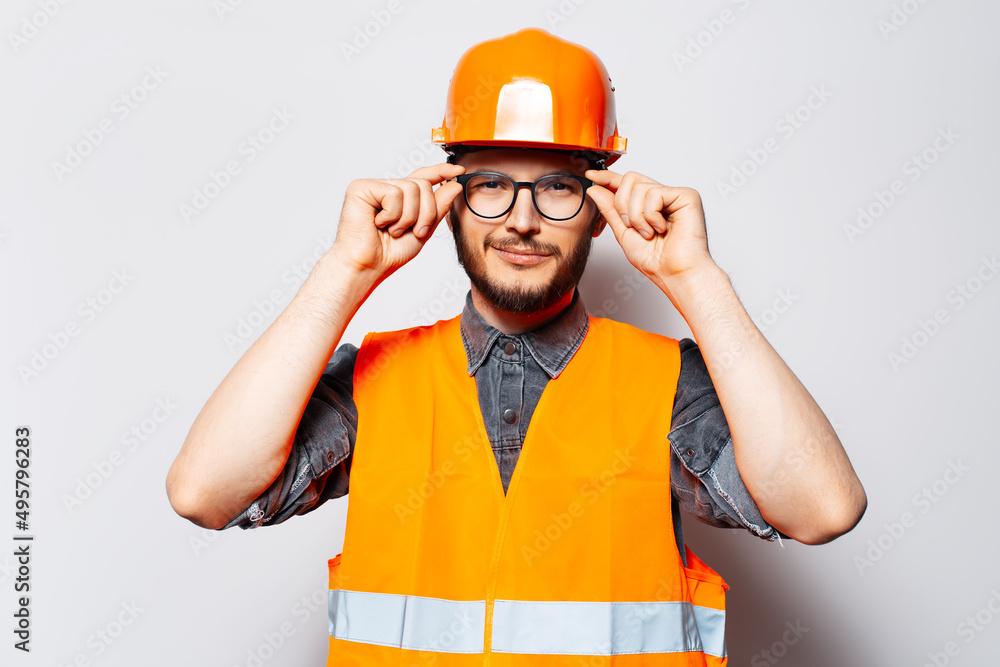 Studio portrait of confident construction worker. Holding glasses with hands.