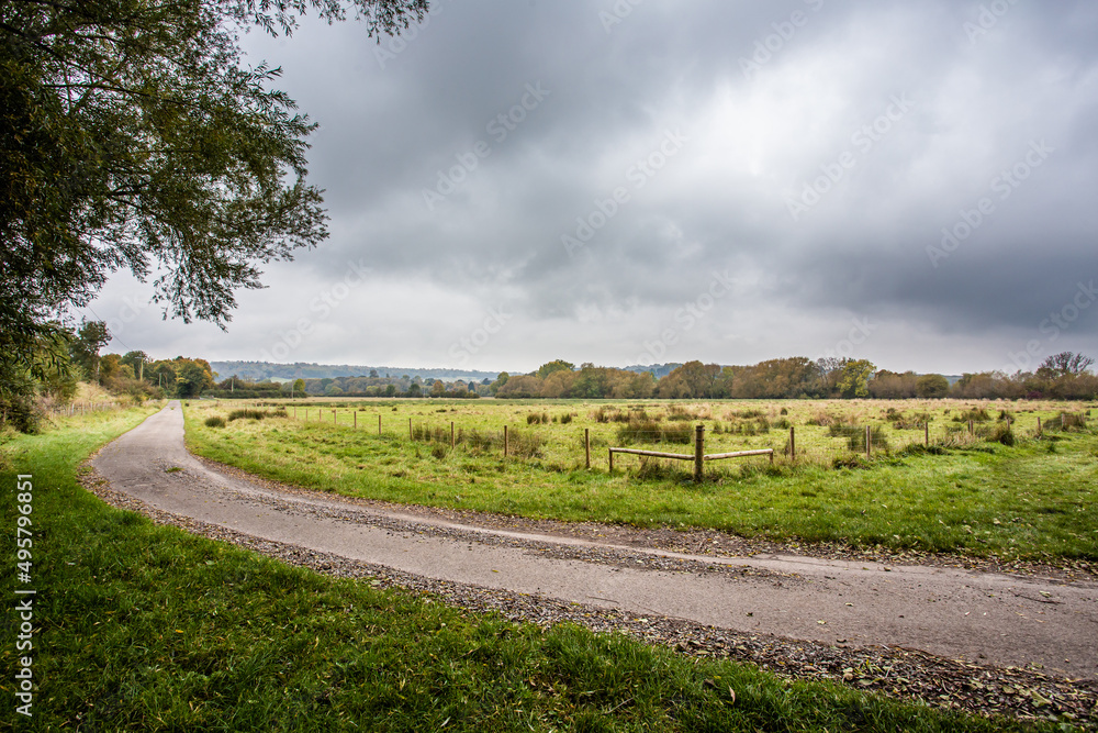 Footpath or bridleway and a green field under the stormy sky
