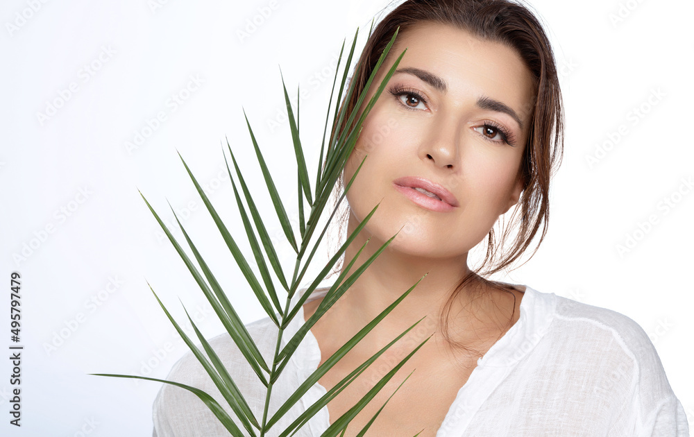 Beautiful natural young woman with nude makeup on a flawless skin and a tropical leaf. Natural cosmetics and skincare concept Beautiful natural young woman with nude makeup on a flawless skin and a tropical leaf. Natural cosmetics and skincare concept