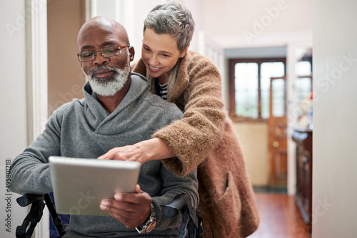 All that matters is that were together. Cropped shot of an affectionate senior couple using a tablet at home with the man sitting in a wheelchair.