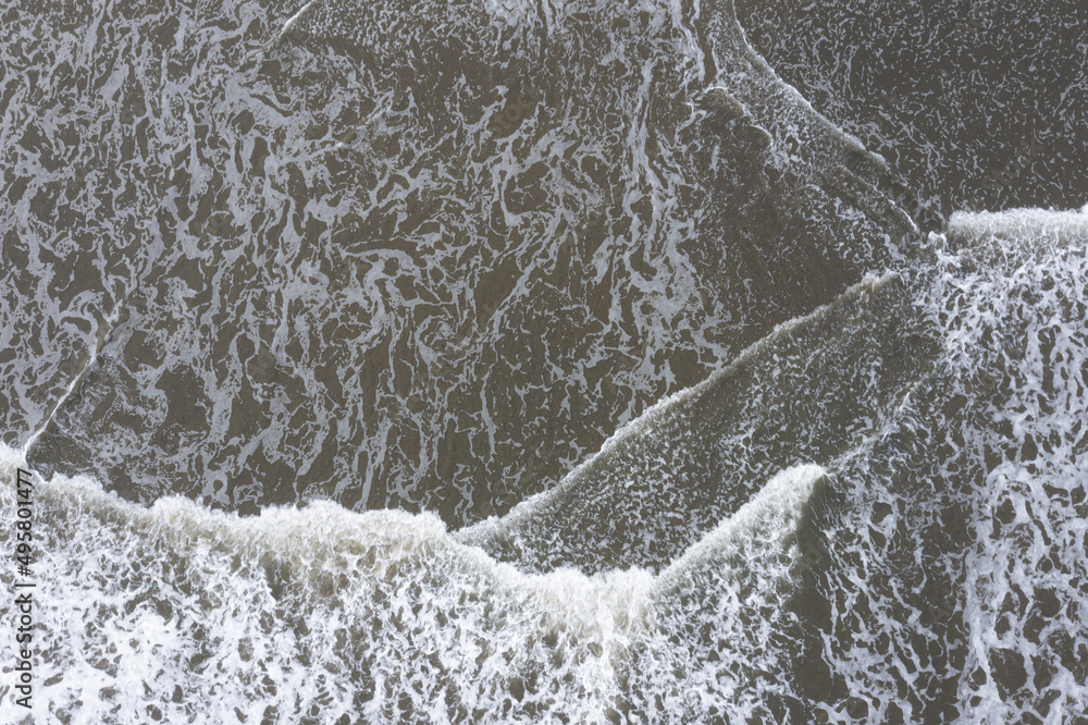 Aerial top view of waves, foam of the waves are making for a beautiful abstract pattern in the ocean Aerial top view of waves, foam of the waves are making for a beautiful abstract pattern in the ocean