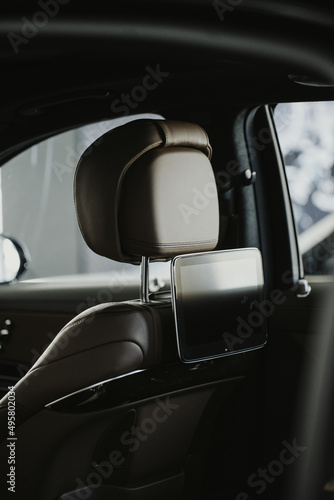 Vertical shot of headrest and a tablet in a luxury black car showroom