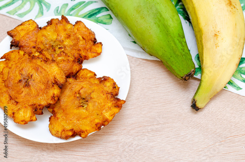
Patacones or fried tostones of green or ripe plantain, with a crispy texture. Traditional Colombian food, on a light wooden background, top view. Flat lay. Copyspace. photo