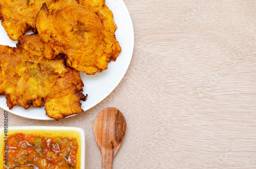 Patacones or fried tostones of green or ripe plantain, crispy, with tomato and onion stew called 