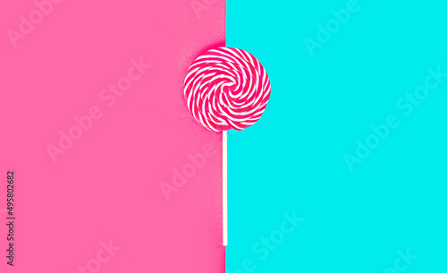 Close up colorful lollipop caramel on stick on pink blue background