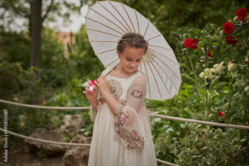 Communion girl posing with a white umbrella in a park photo