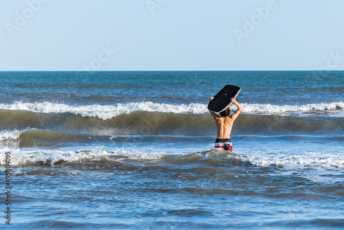 Teenage Boy With Black Bodyboard in the Ocean