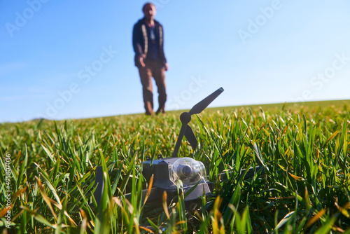 shocked man with broken drone. Worried man with crashed gadget. Excited young man (disappointed man) with drone which falls down on field. Selective focus to foreground