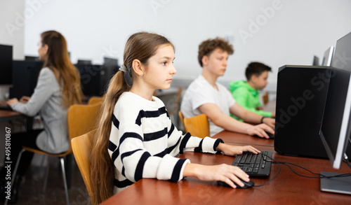 Modern teen schoolgirl learning basics of programming in group course in computer college..