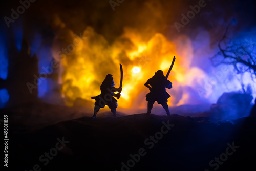 Samurai fighting concept. Silhouette of samurais in duel near tree and old temple. Table decoration with dark toned foggy background. Selective focus